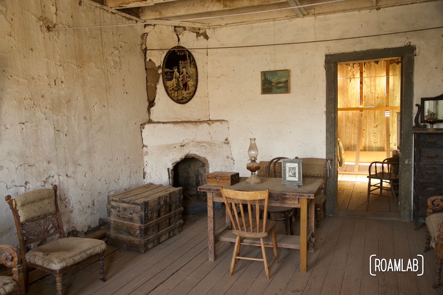 Wood table and chairs by an old stucco fireplace in a historic boarding house in Shakespeare Ghost Town, New Mexico.