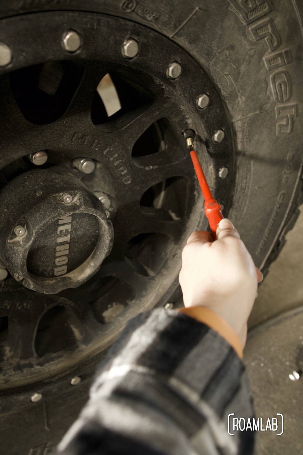 Hand using a screwdriver to air down tires.