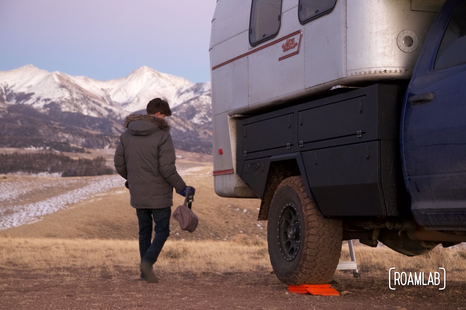 Man transferring gear from a Bowen Customs aluminum truck bed to a 1970 Avion C11 truck camper.