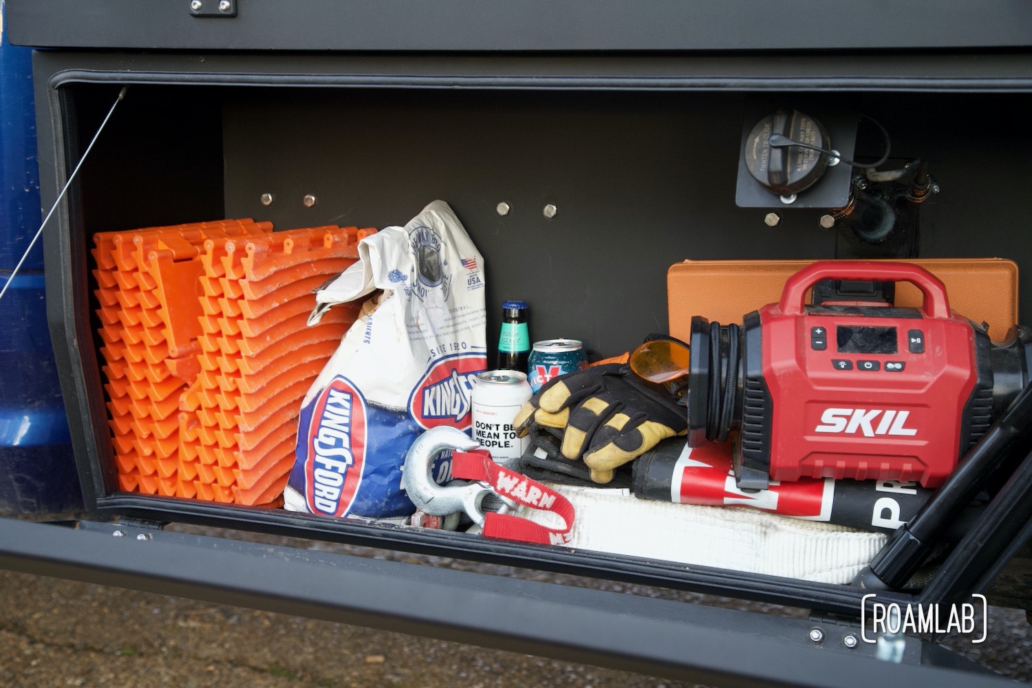 View in a Bowen Customs truck bed lower front storage box loaded with treads, coal, straps, and tire inflation.