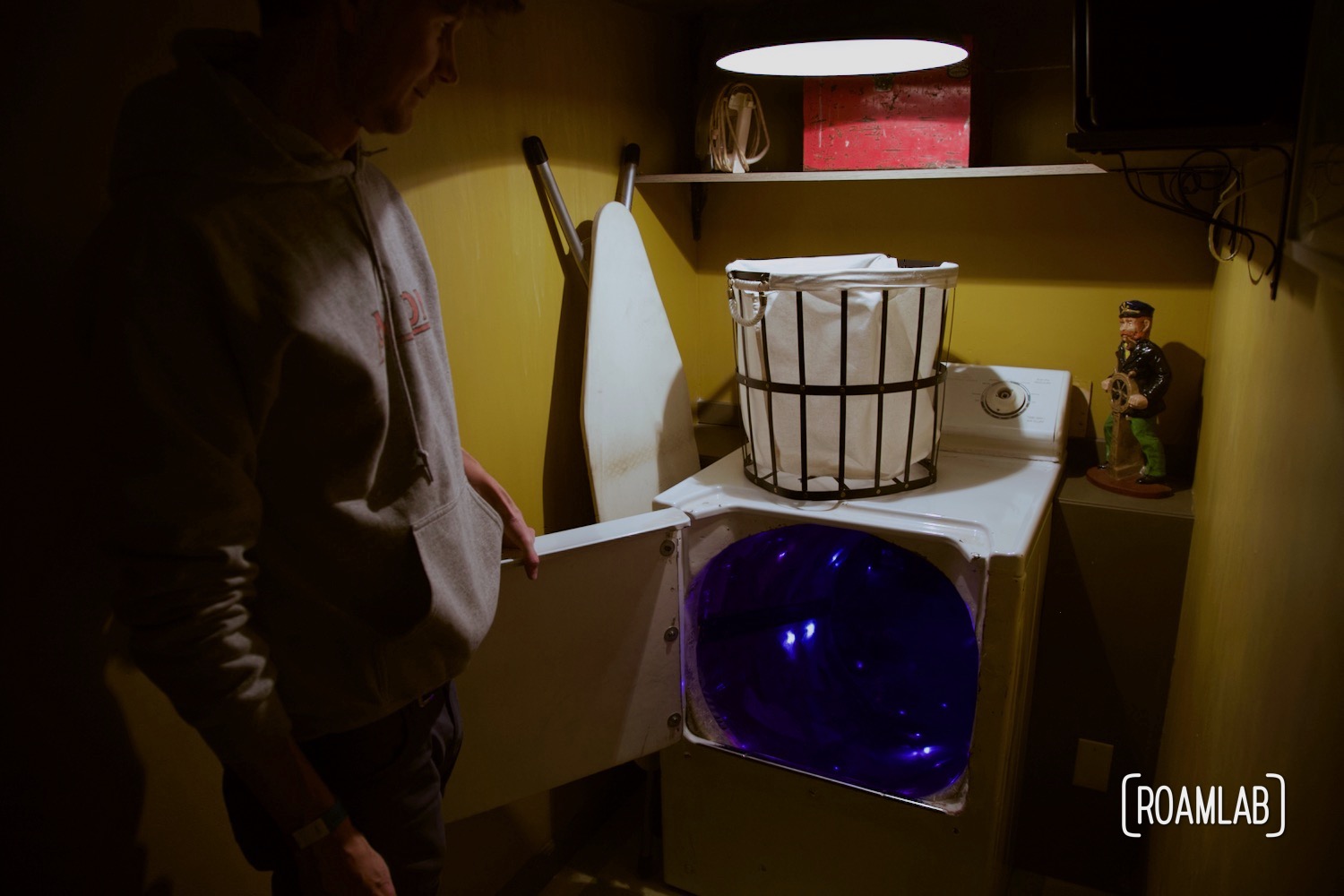 Man looking into an illuminated laundry dryer at the House of Eternal Return, Meow Wolf's Santa Fe, New Mexico Location