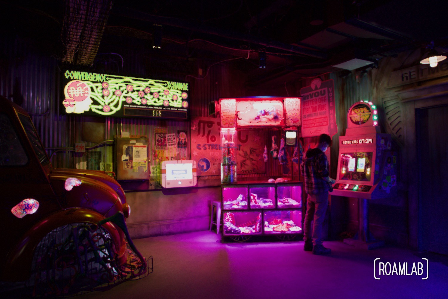 Man standing next to the voting machine on the Cyberpunk inspired metropolis of C Street at Convergence Station, Meow Wolf's Denver, Colorado location.