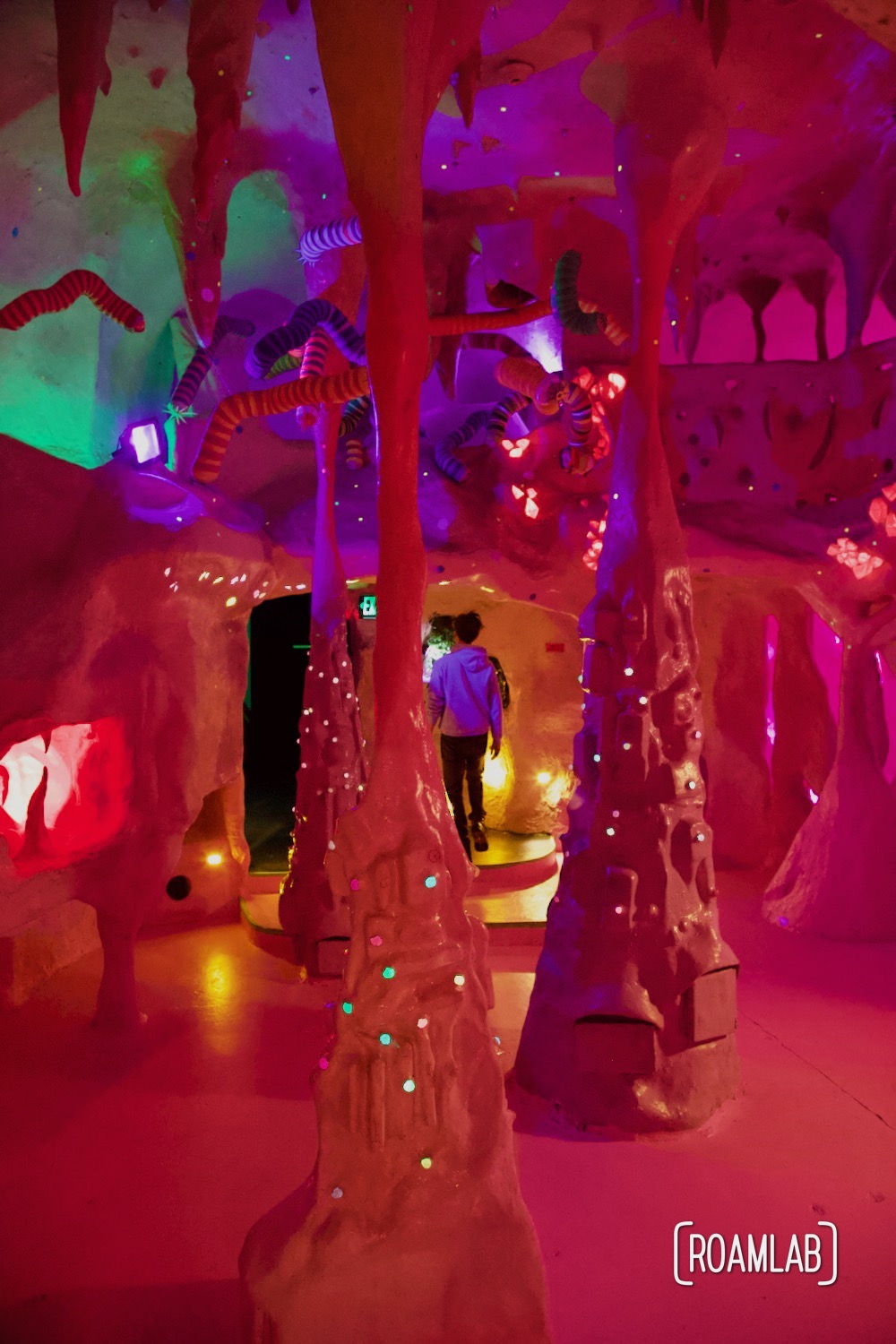 Man wandering through a strange and colorful cavern at the  House of Eternal Return, Meow Wolf's Santa Fe, New Mexico Location