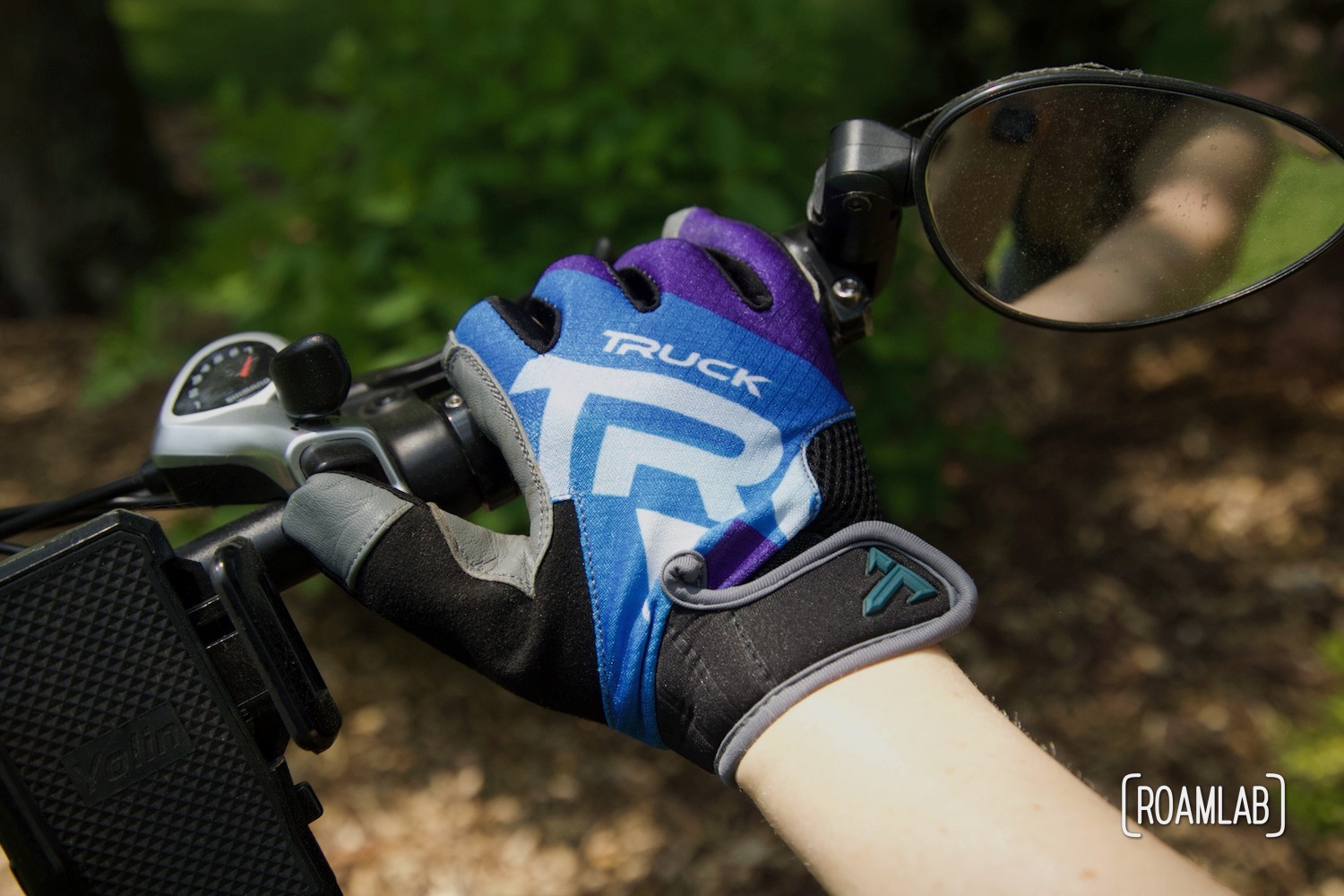 Gloved hand holding a bicycle handle.