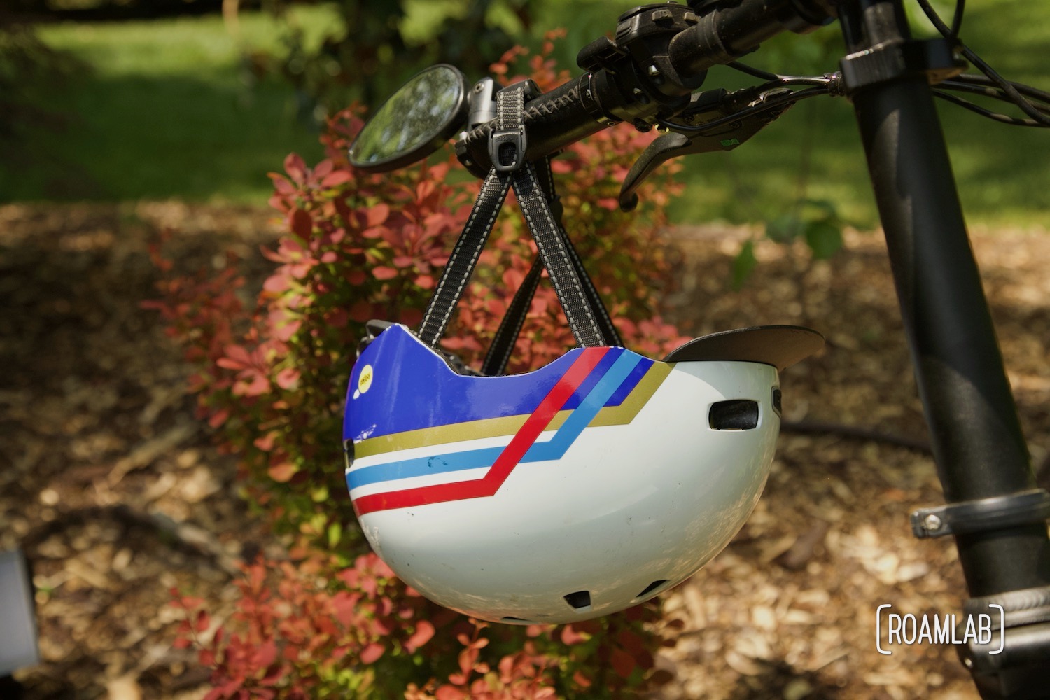 Colorful helmet hanging on bicycle handle bars.