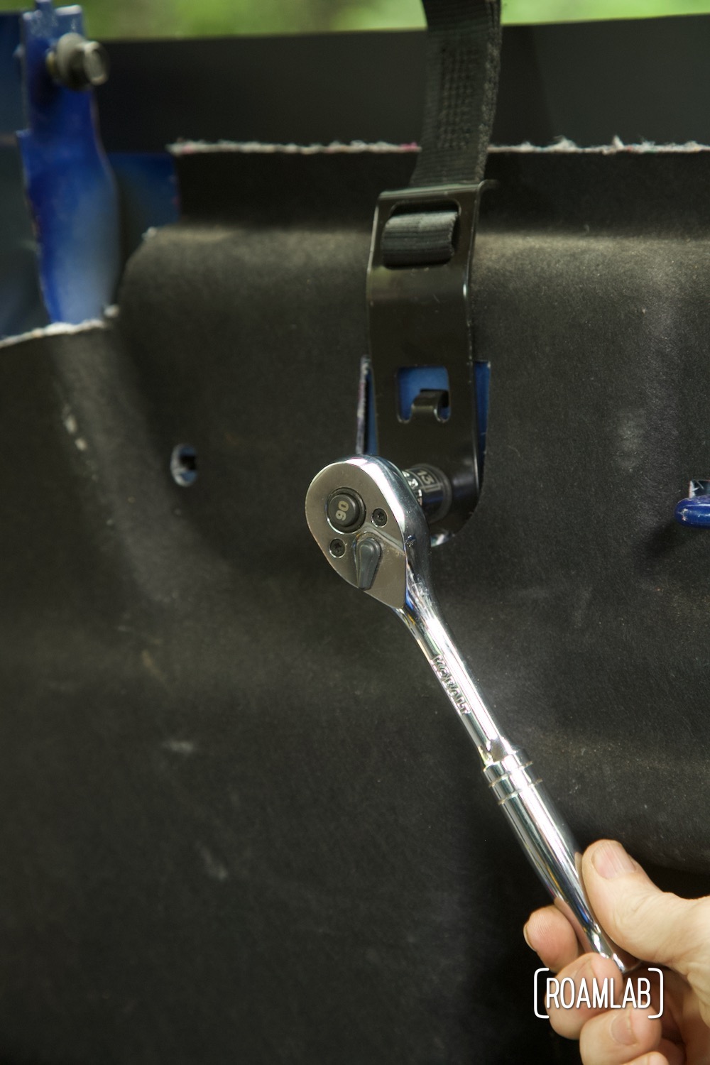 Hand ratcheting a bolt off a truck cab interior panel.