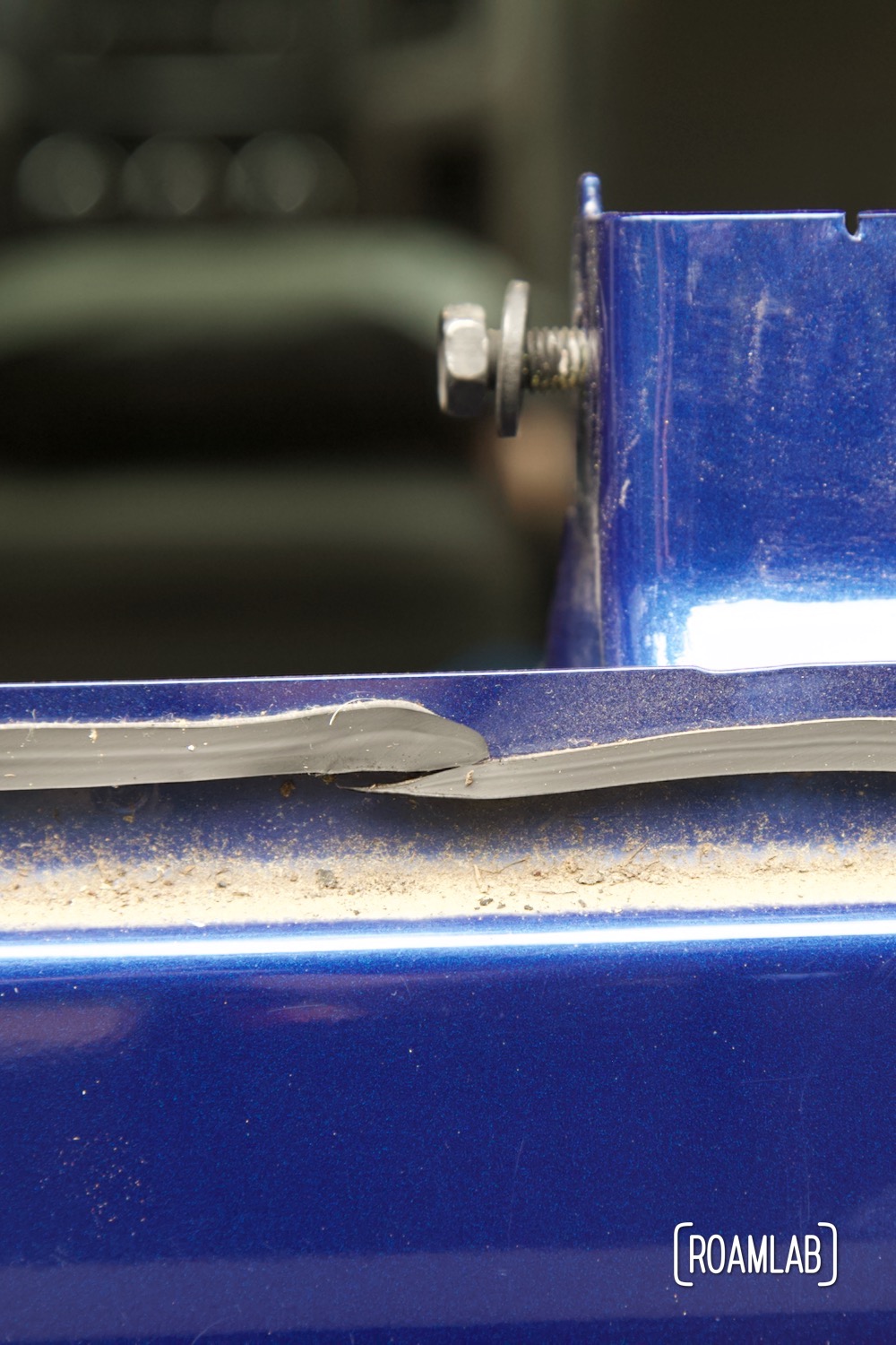 A flat but thick line of exposed urethane along the blue metal window frame of the rear truck cab.