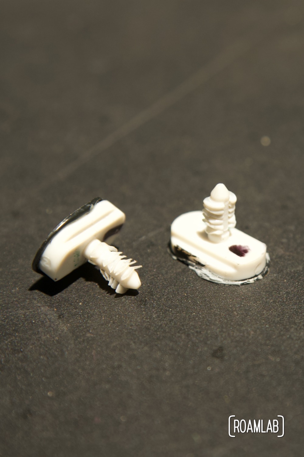 Two plastic white spacers sitting on a black surface.