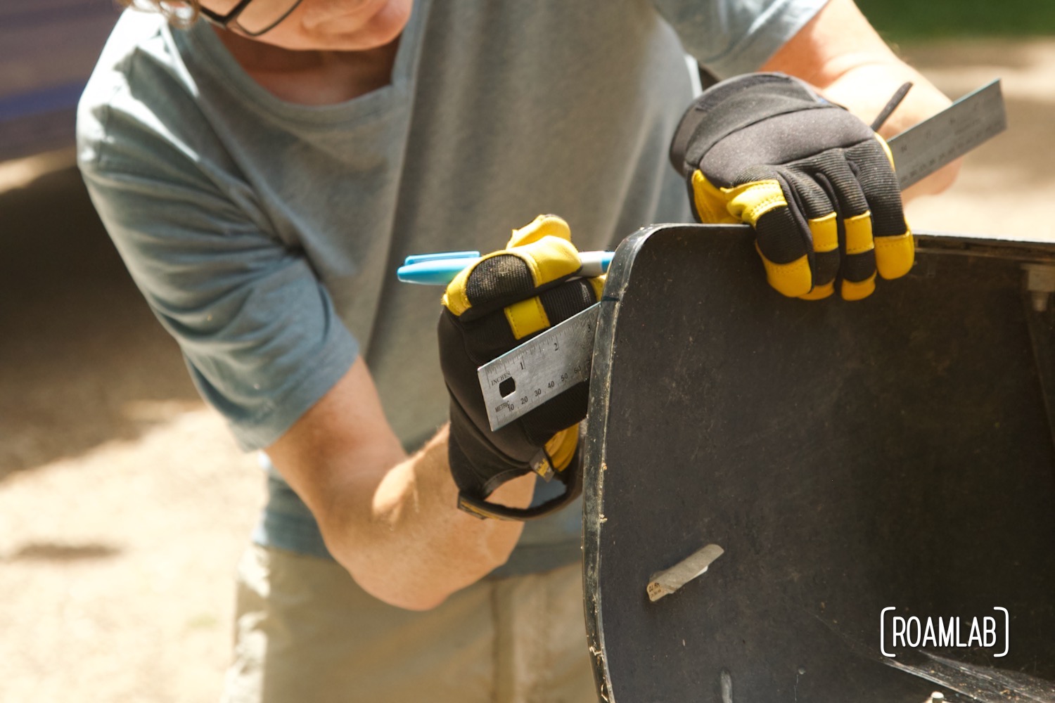 Man using a ruler to draw a line on a bumper.