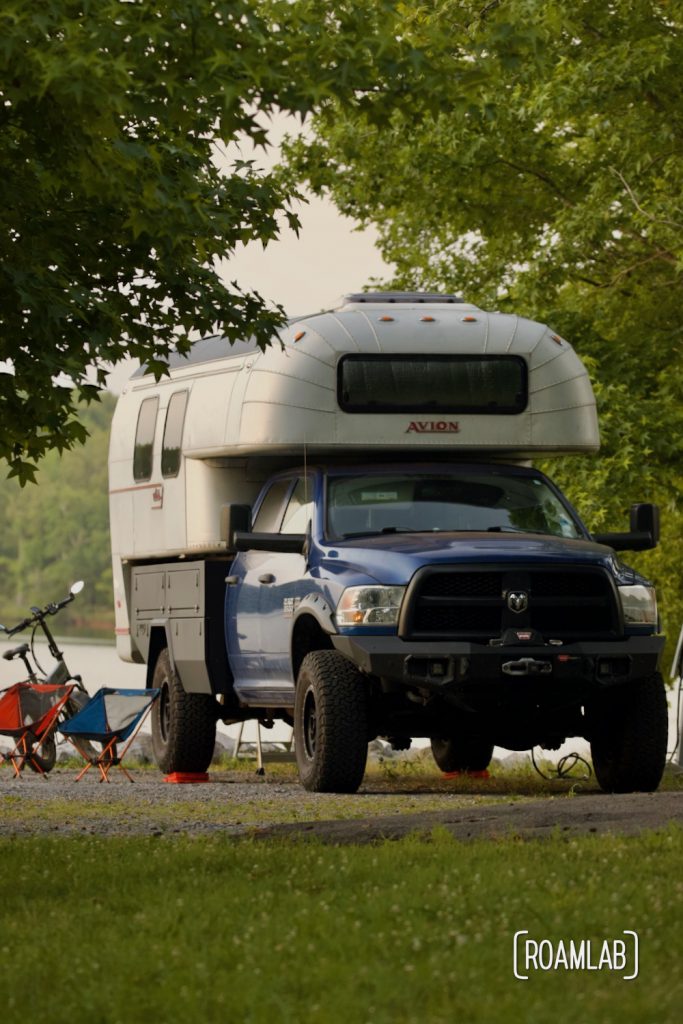 Avion C11 truck camper parked on the shore line under the shade of a tree.