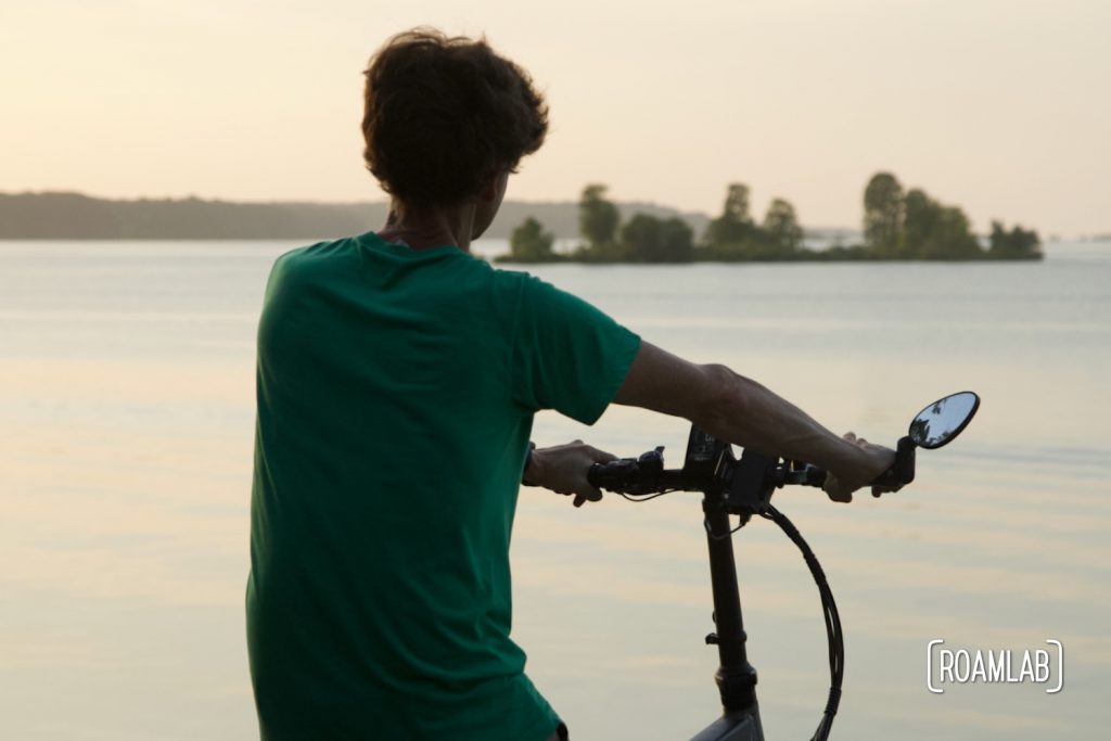 Man riding a bike by a lake.