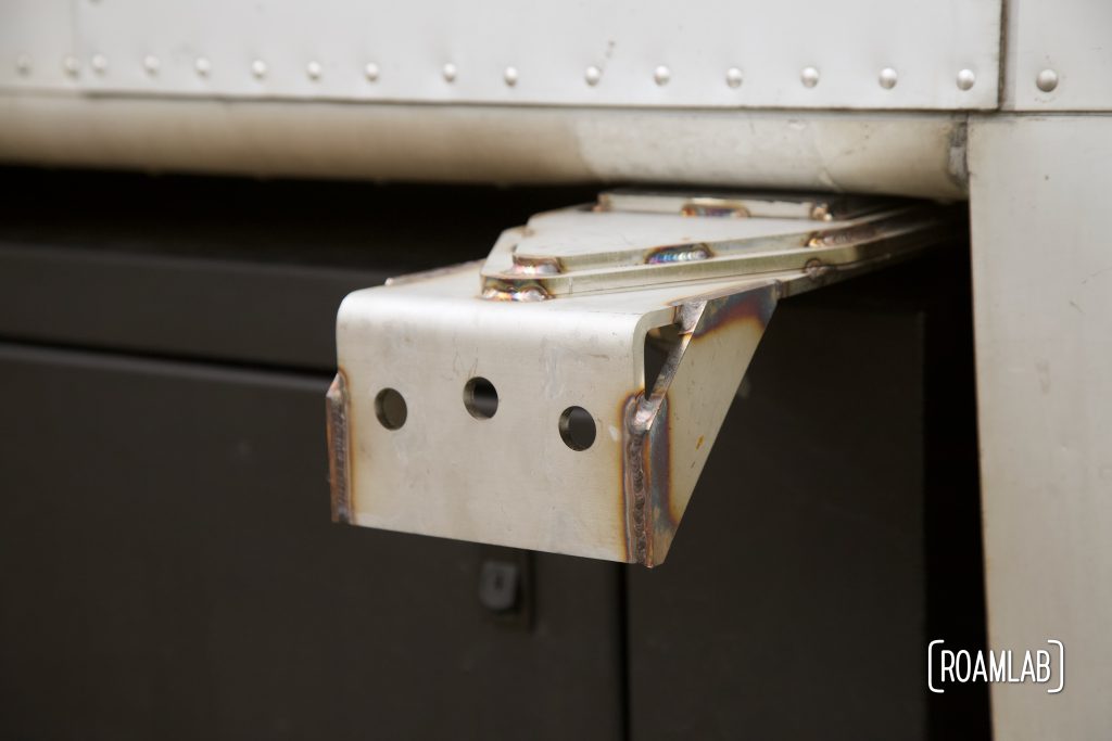 Side view closeup of quick-release bracket attached to truck camper wing.