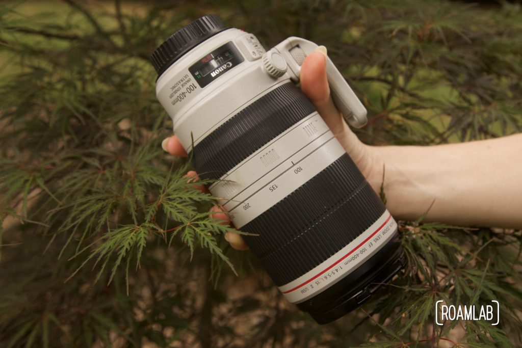 Handing holding a large gray and black camera lens.