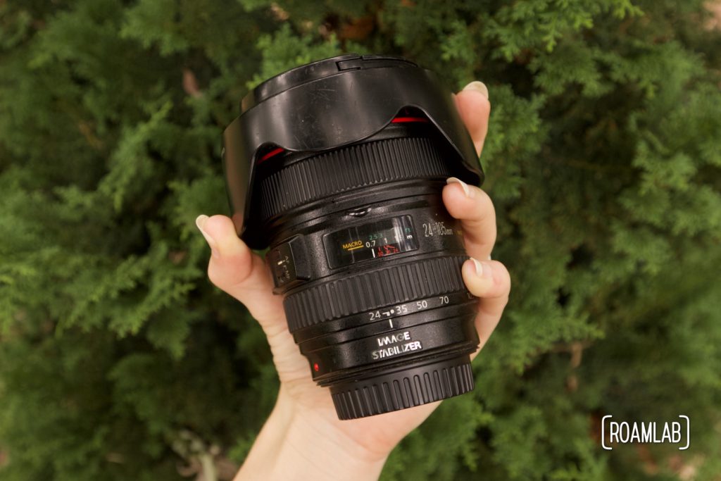 Hand holding a black camera lens.