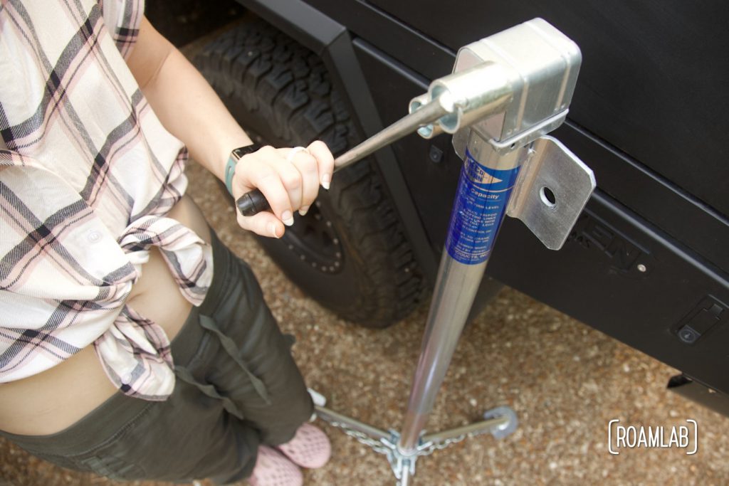 Hand holding a manual crank to a truck camper jack.