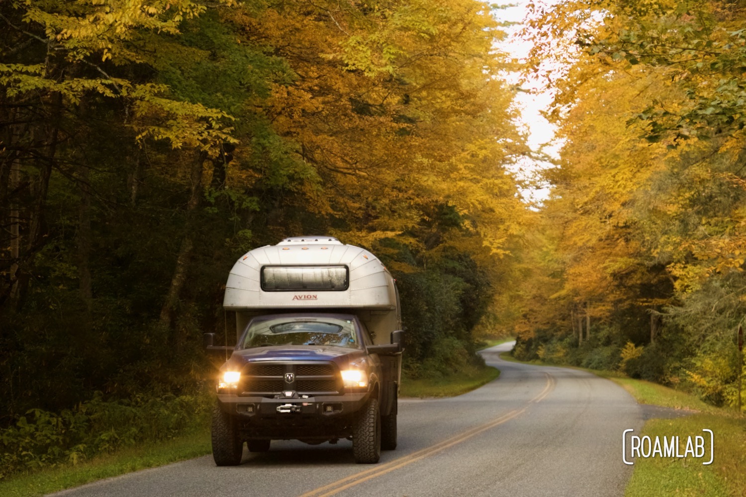 1970 Avion C11 truck camper surrounded by golden trees along Blue Ridge Parkway.