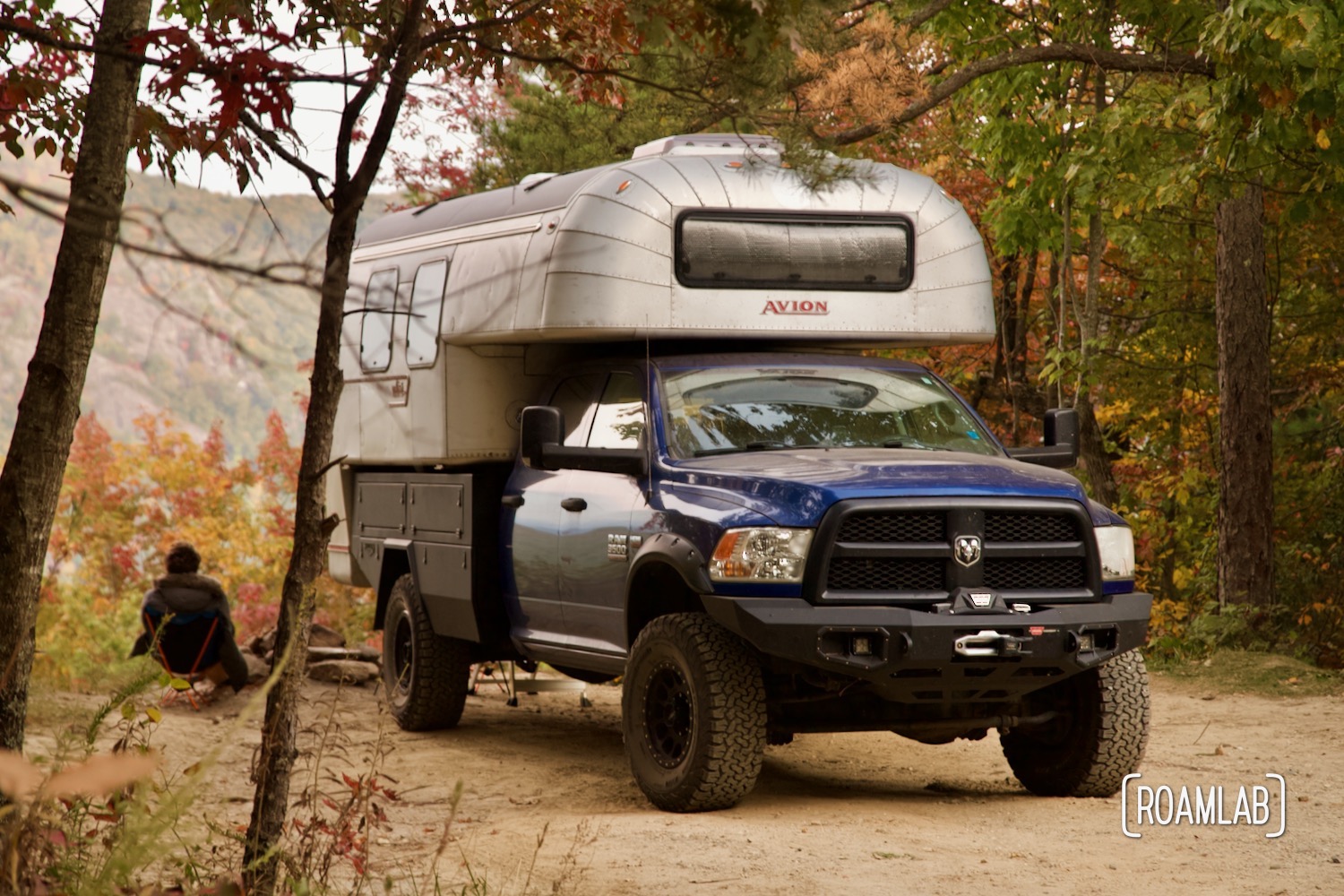 Man sitting next to a 1970 Avion C11 truck camper boondocking off of Old North Carolina 105 in Linville Gorge Wilderness Area.