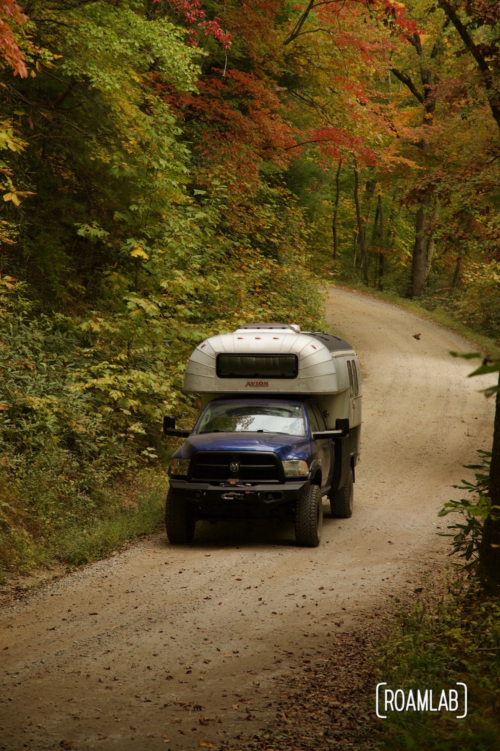 1970 Avion C11 truck camper winding along the dirt Old North Carolina 105 in Linville Gorge Wilderness Area.