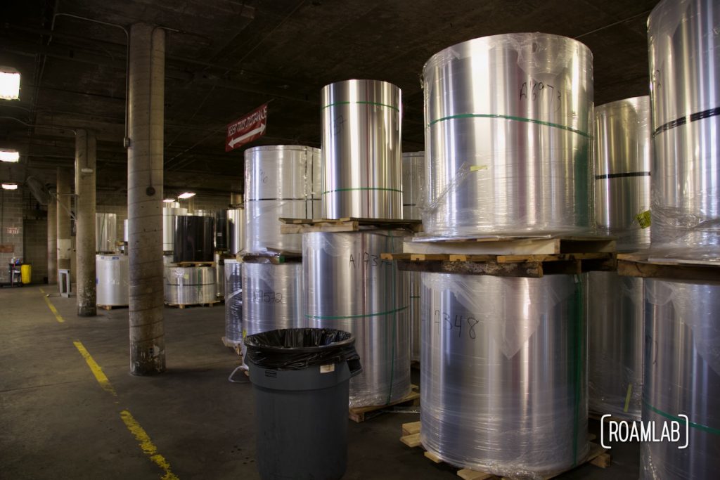 Stacked rolls of aluminum sheets in a warehouse.