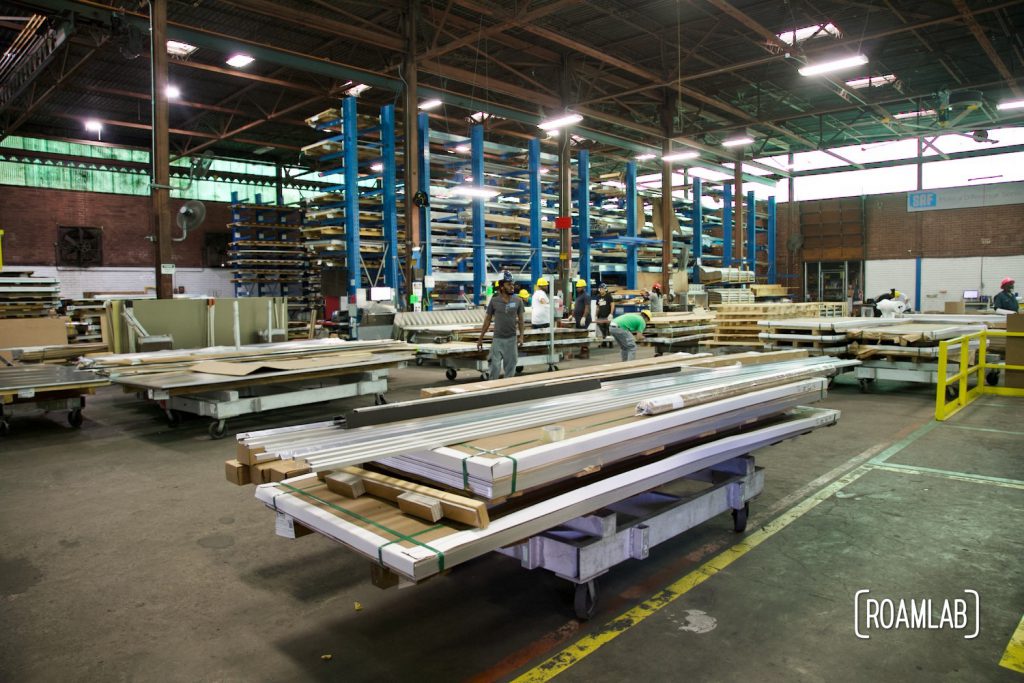 Interior warehouse view of stacks of aluminum sheet being sorted in large frames.