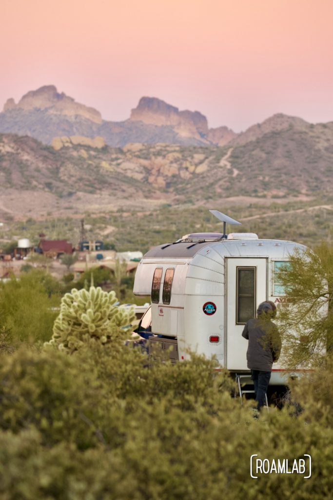 Man opening the door to a 1970 Avion C11 truck camper in the desert at sunrise.