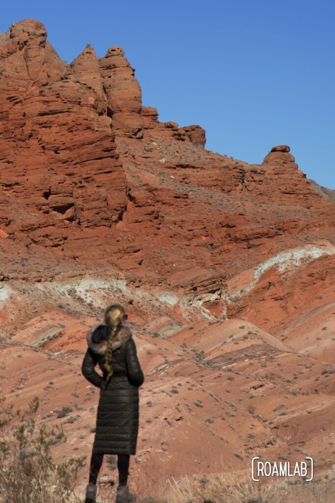 Woman dwarfed by red rock formations.